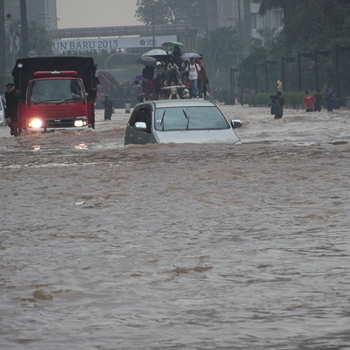 A car and truck driving through floodwaters in Jakarta, Indonesia