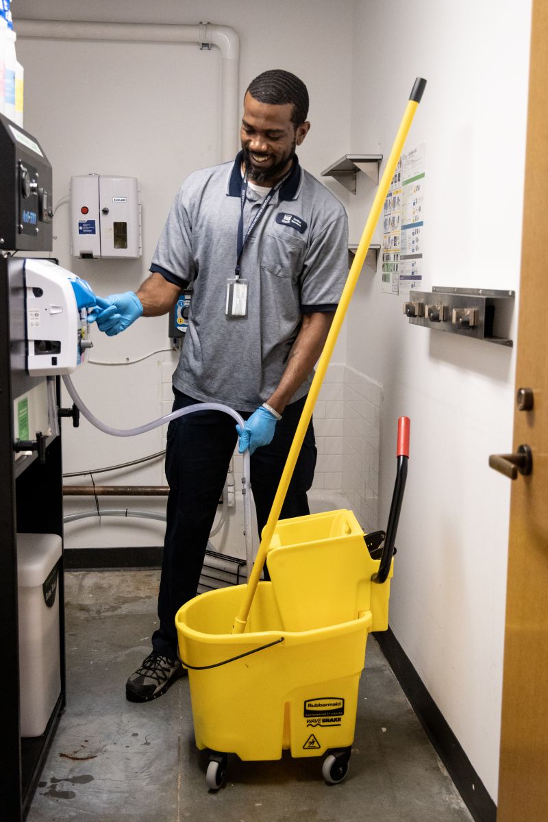 Yale custodian filling a mop bucket with green cleaning solution