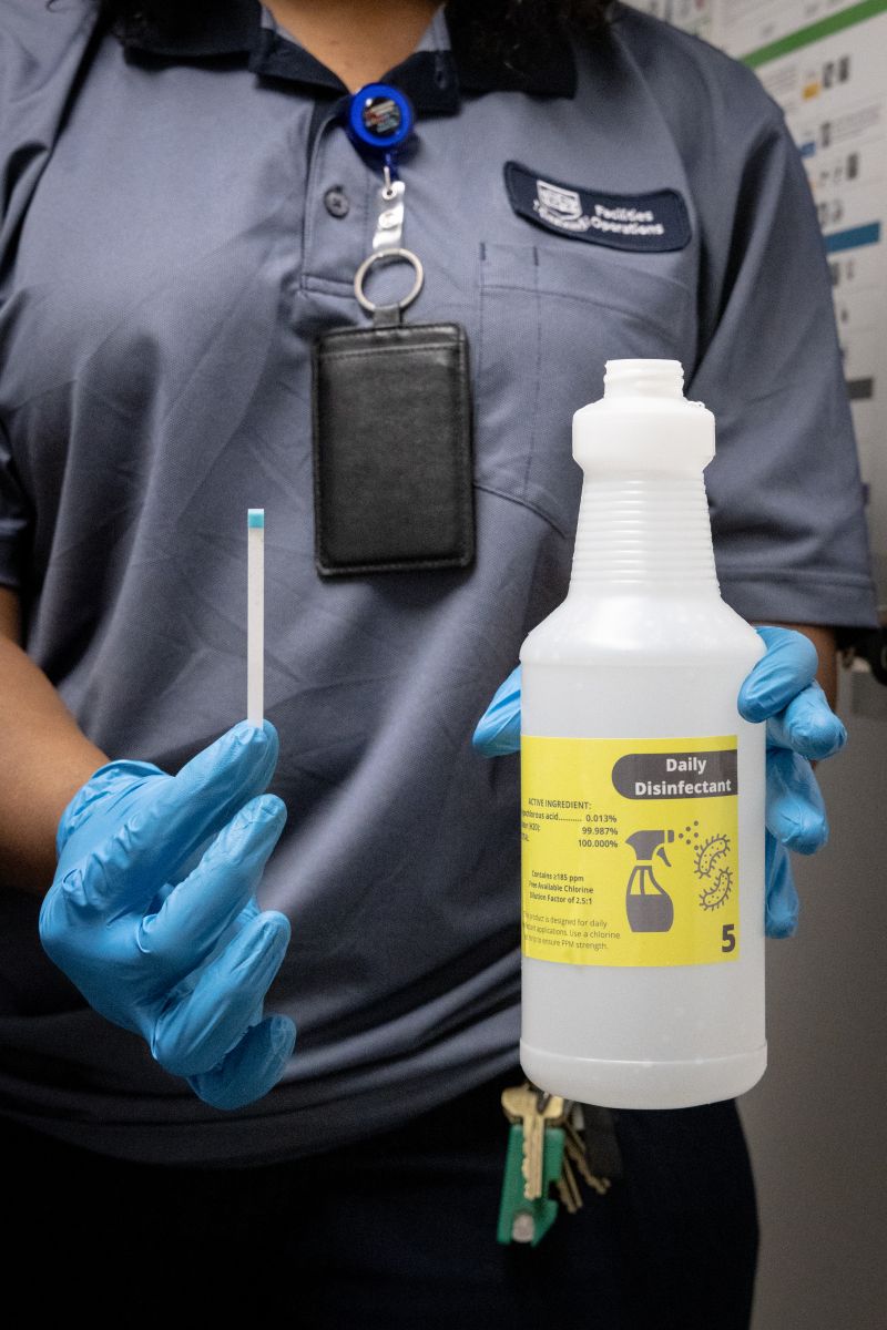 Yale custodian with blue gloves holding a pH test strip