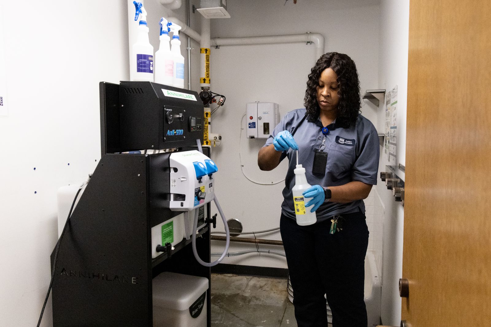 Yale custodian dipping a pH test strip into a bottle of cleaning solution