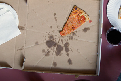 Overhead view of a pizza box with one slice left