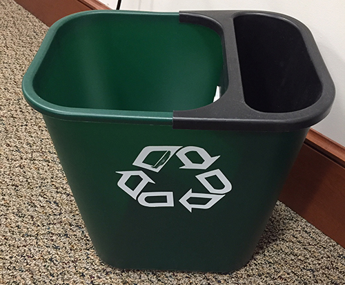 An under-desk recycling bin for mixed paper with a printed label of the allowed materials.