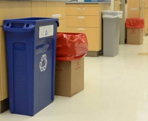  a blue plastic recycling bin next to a bin labeled &quot;biohazard&quot;.