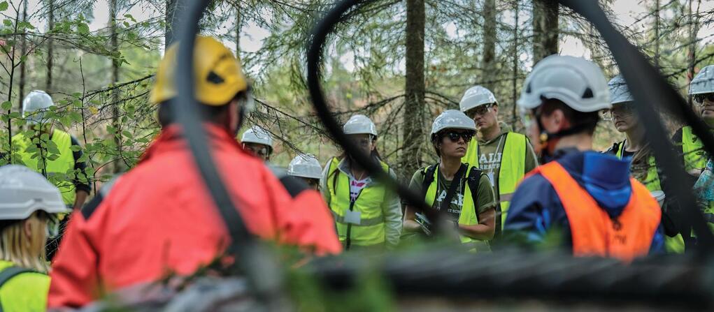 A photo of participants in hardhats touring a forest in Finland