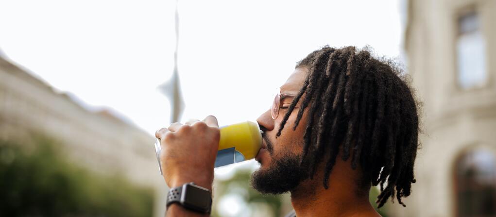 A photo of a man drinking a cold beverage in a hot city