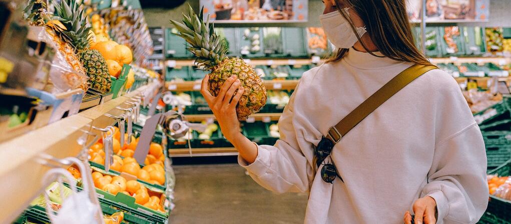woman at the grocry store looking at a pineapple