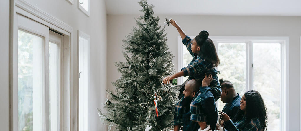 family putting a star on top of a christmas tree