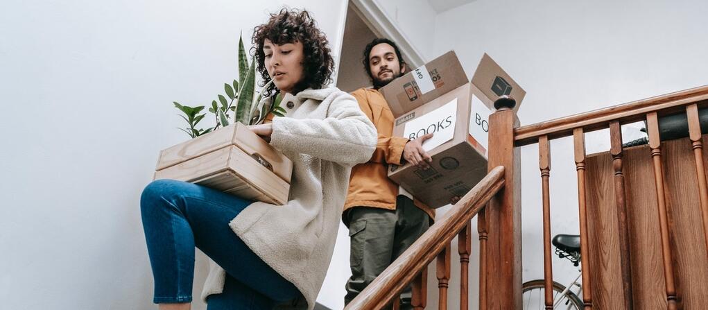 a couple carrying boxes downstairs