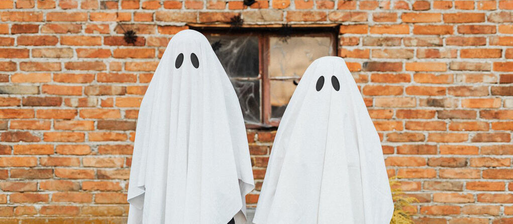 kids in ghost costumes against a brick wall