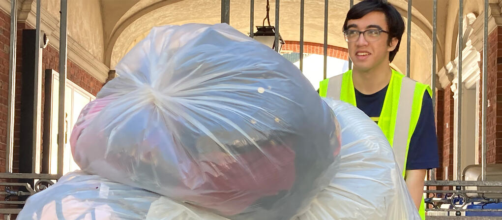 Spring Salvage student worker Xander Calictan ’25 wheels a cart of clothes during student move-out.