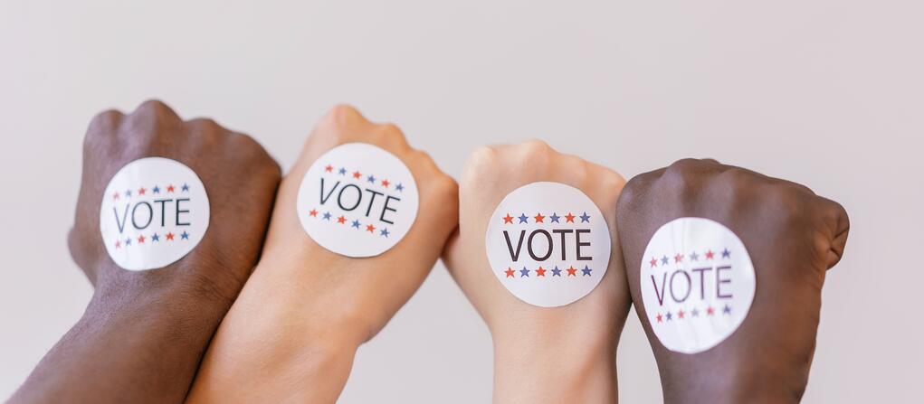 Four hands with 'Vote' stickers on them