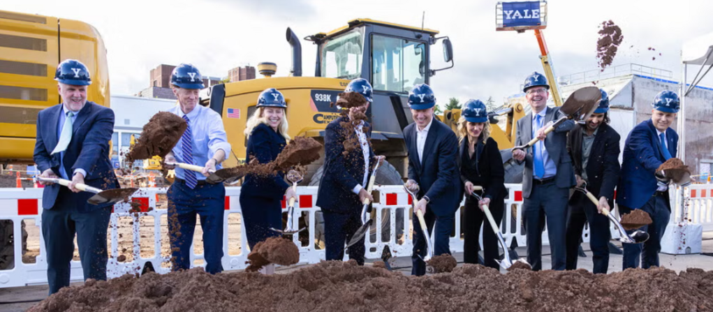 Group of Yale officials flinging shovels of dirt at a groundbreaking