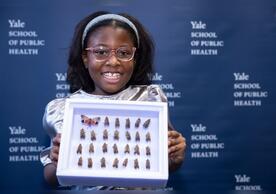 A photo of 9-year-old Bobbi Wilson holding a case containing her spotted lanternfly collection