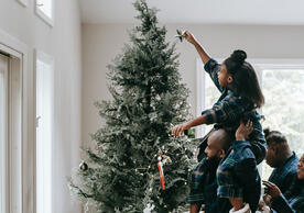 family putting a star on top of a christmas tree