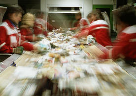 Workers at a recycling center sort through waste moving down a conveyer belt.